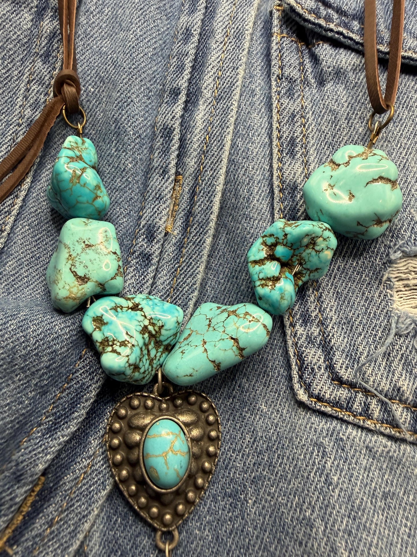 Turquoise stone necklace with a heart-shaped pendant on a denim background