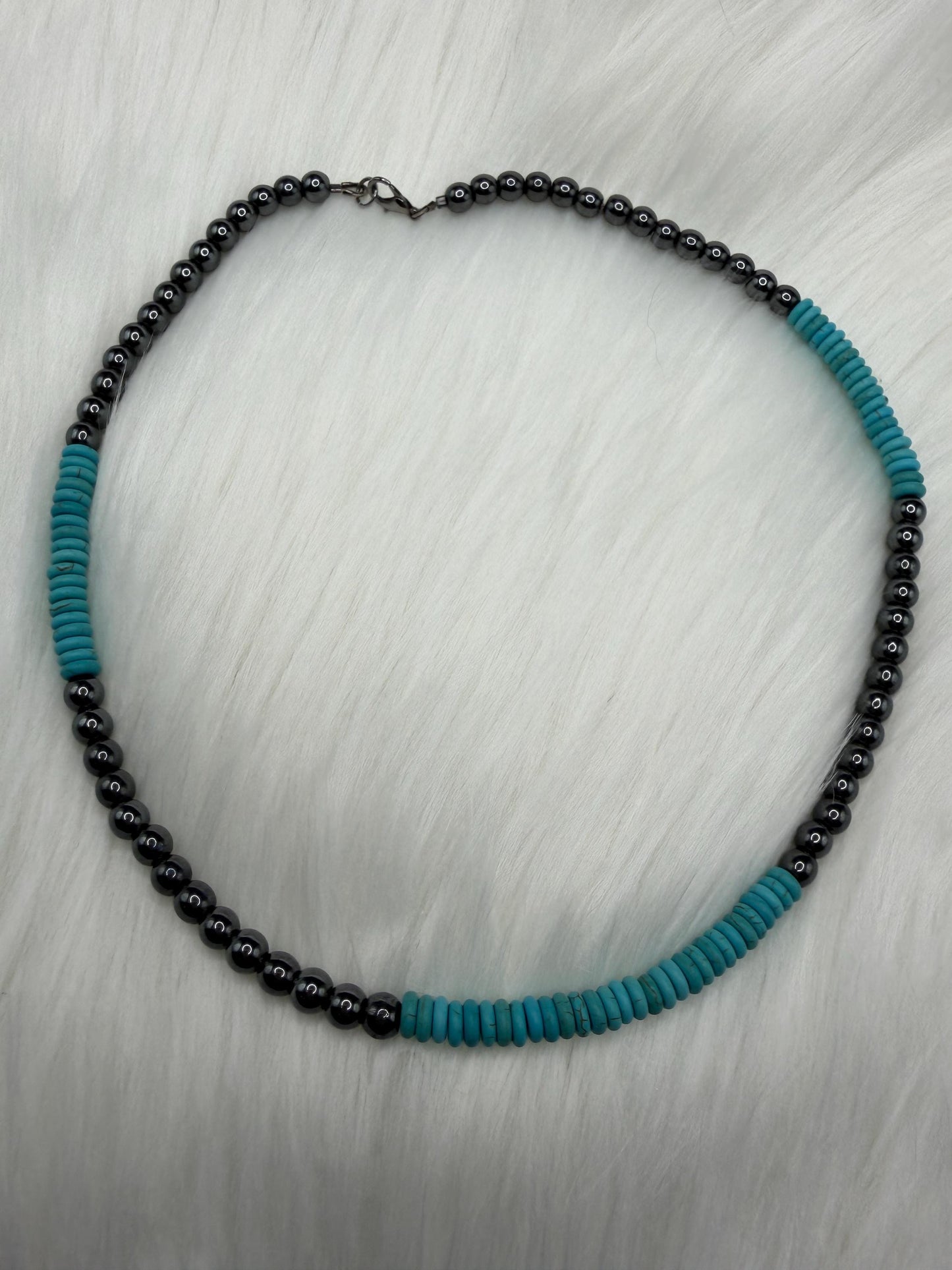 Necklace with hematite and turquoise beads on a light gray background
