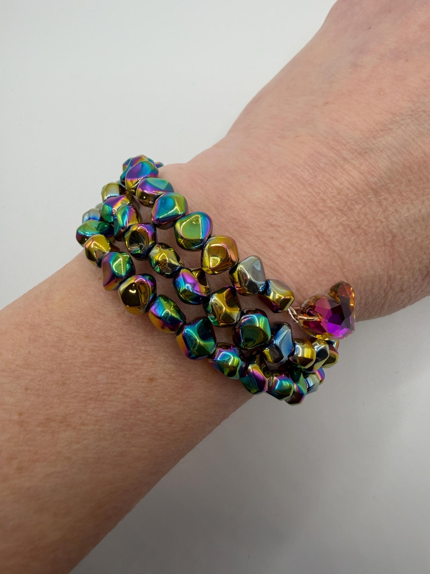 Multicolored beaded bracelet on a wrist against a white background