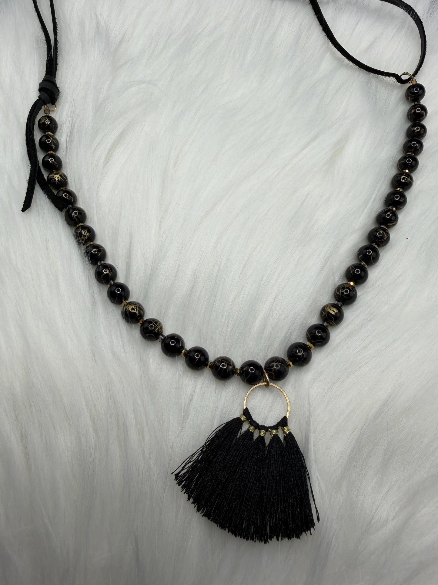 Black beaded necklace with a tassel pendant on a white background