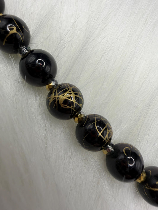 Black beaded necklace with gold accents on a silver background