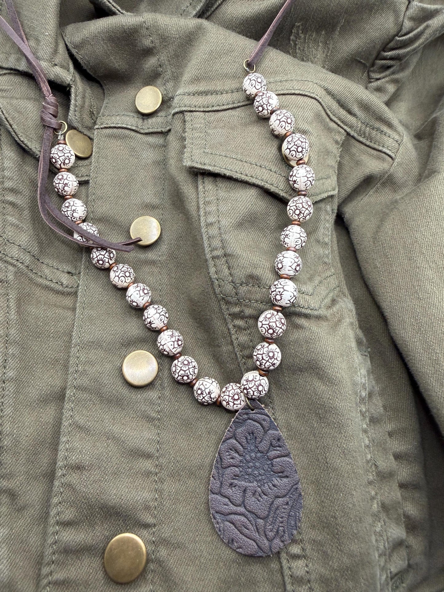 Necklace with decorative pendant on a green jacket