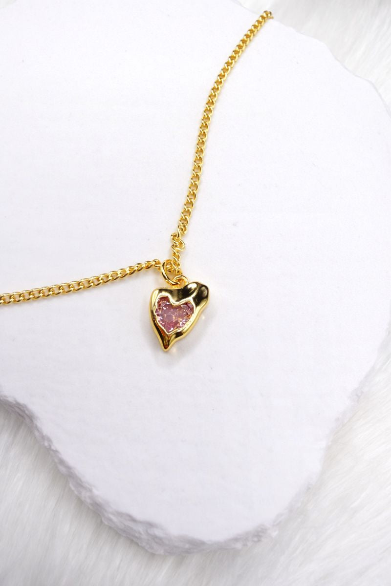 Gold necklace with a heart-shaped pendant on a white background