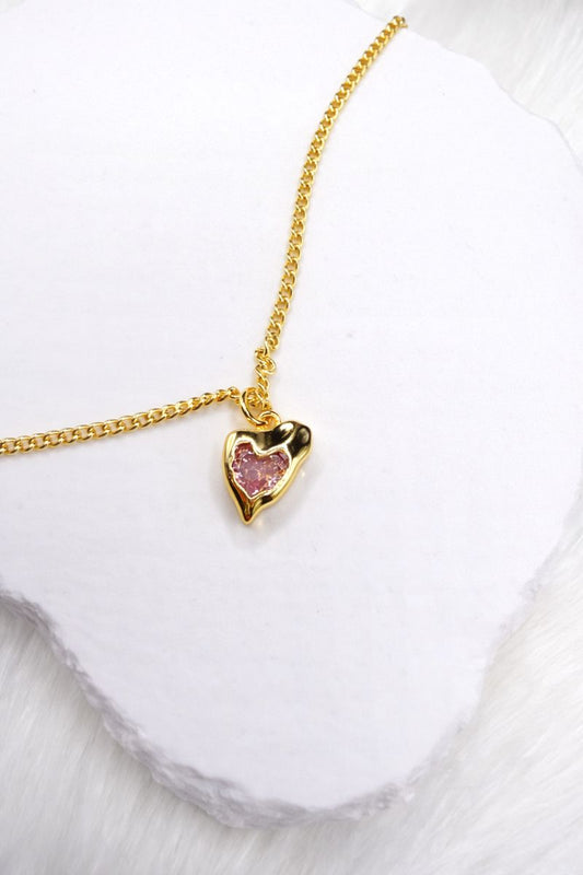 Gold necklace with a heart-shaped pendant on a white background