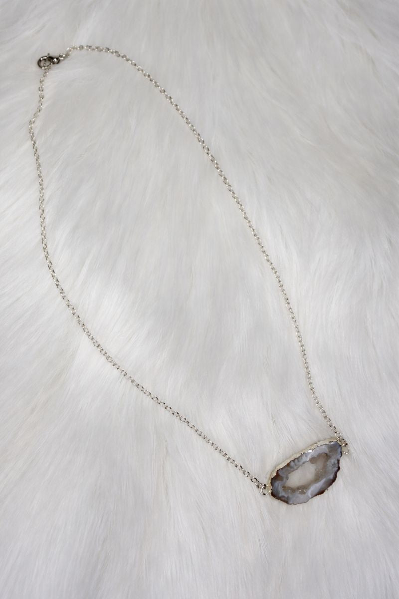 Necklace with a geode pendant on a white fur background