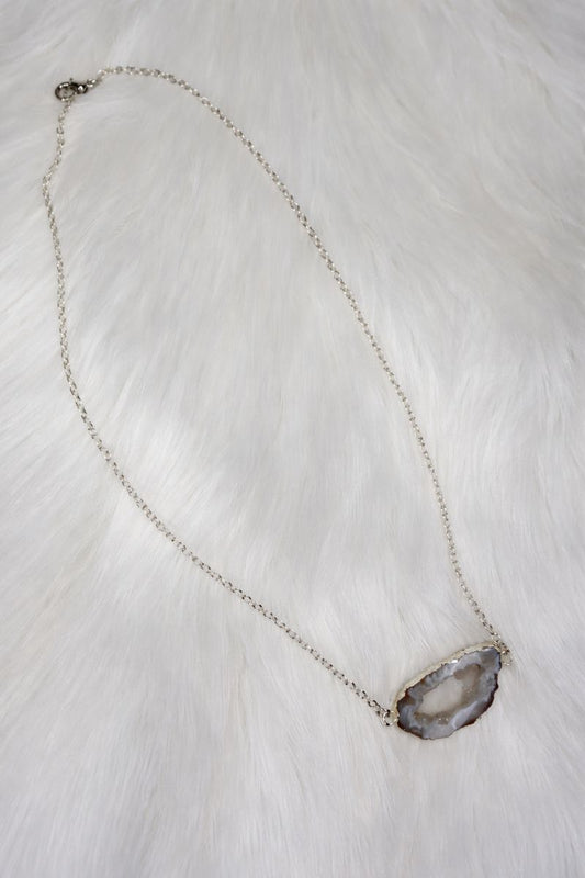 Necklace with a geode pendant on a white fur background