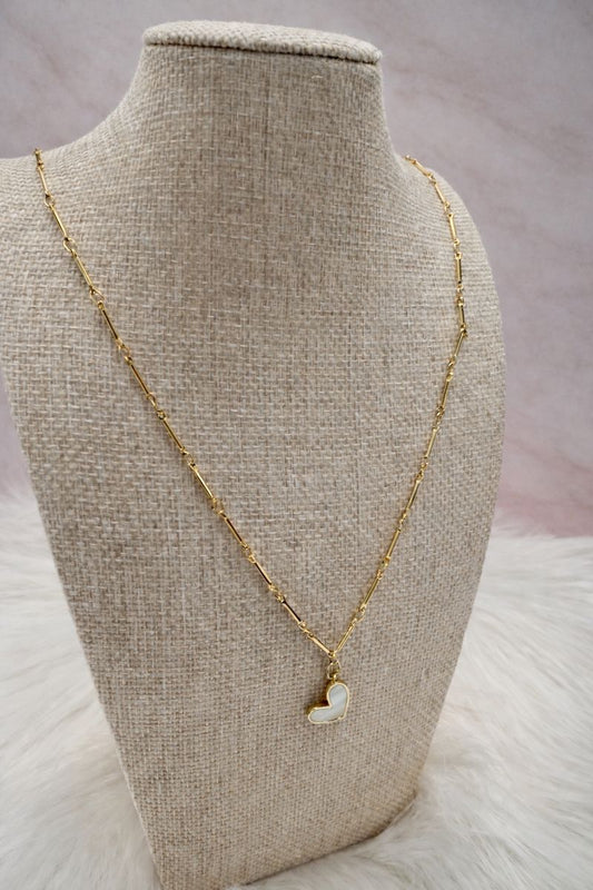 Gold necklace with a heart-shaped pendant on a mannequin bust.