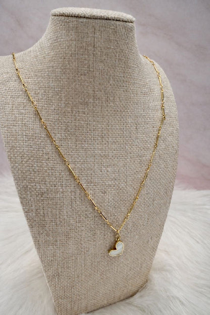 Gold necklace with a heart-shaped pendant on a mannequin bust.