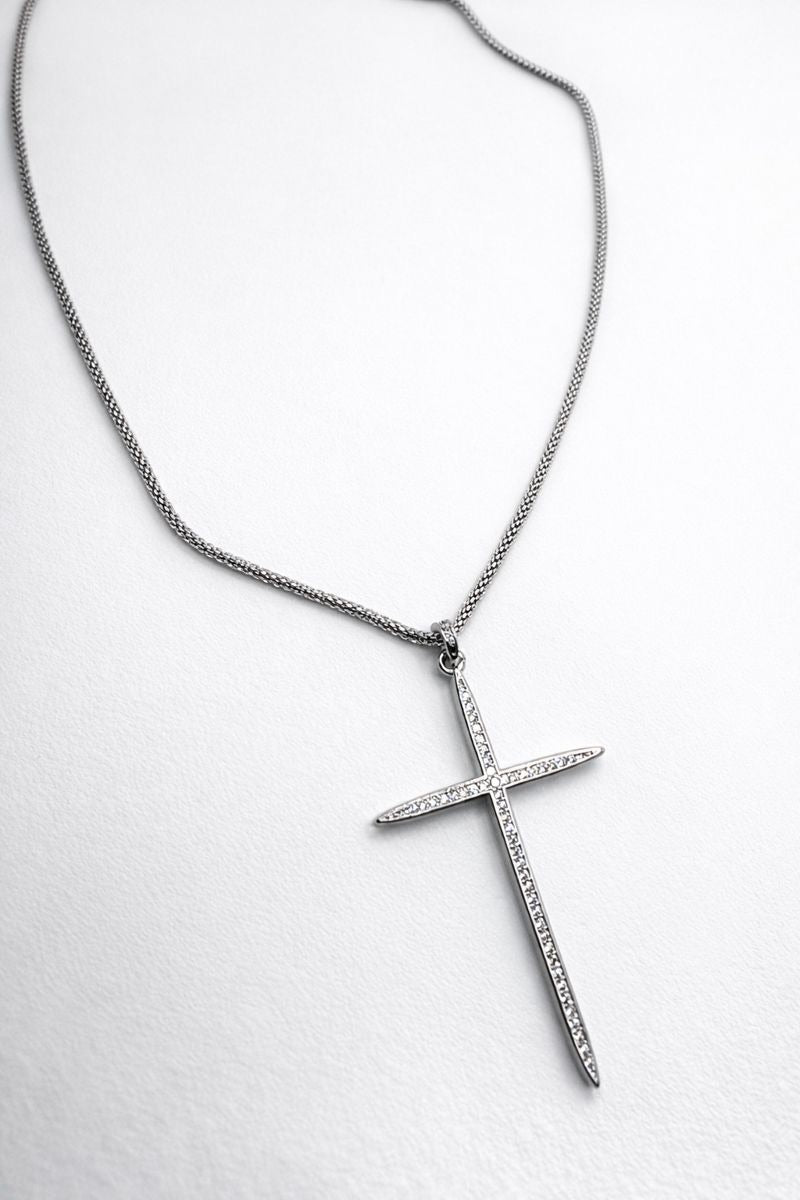 Silver cross pendant necklace on a white background