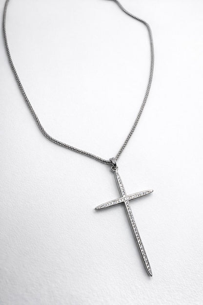 Silver cross pendant necklace on a white background