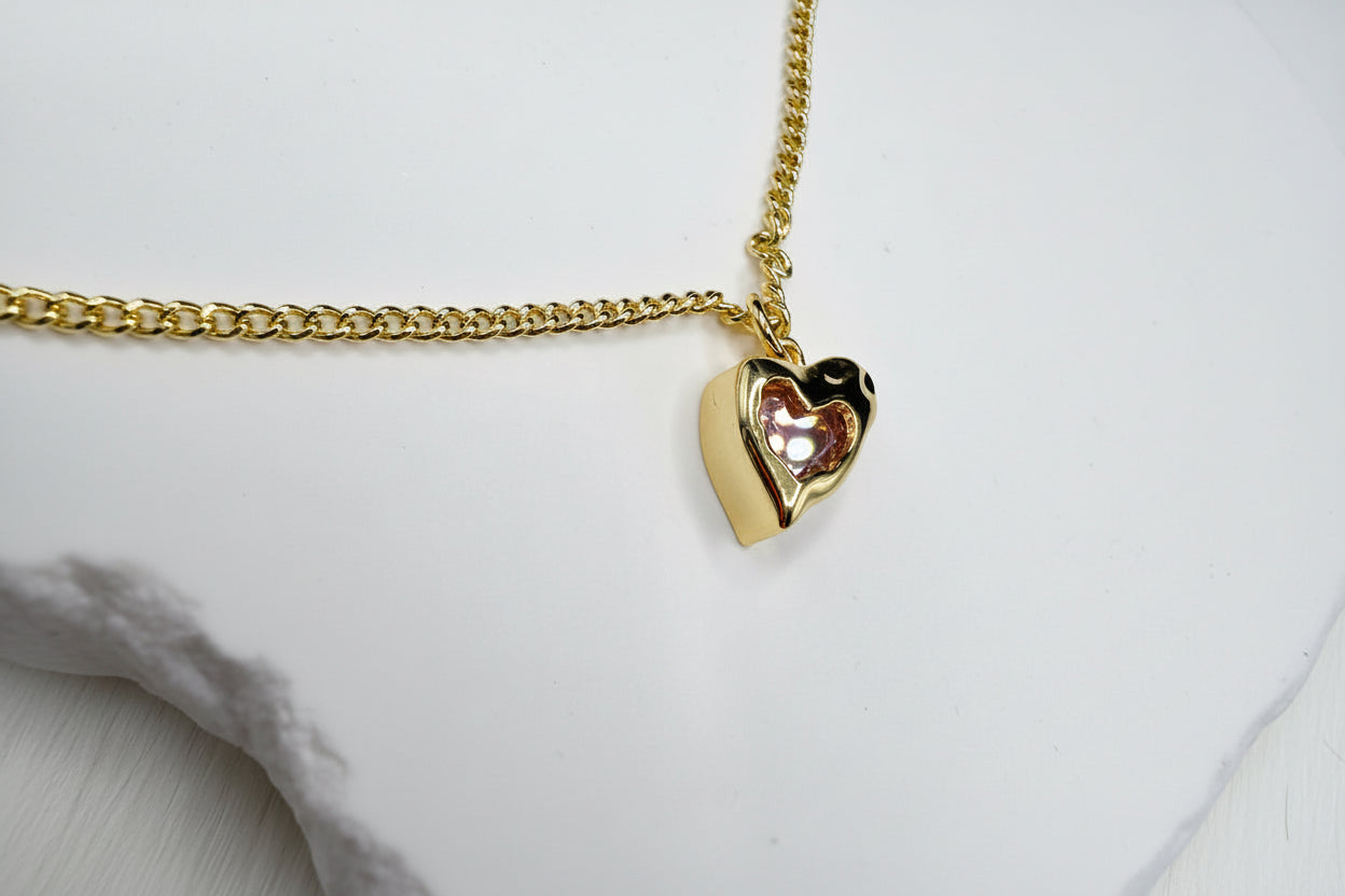 Gold heart-shaped pendant on a chain against a white background