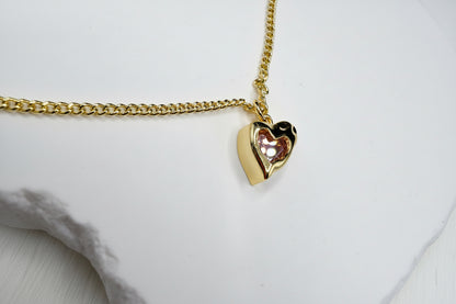 Gold heart-shaped pendant on a chain against a white background