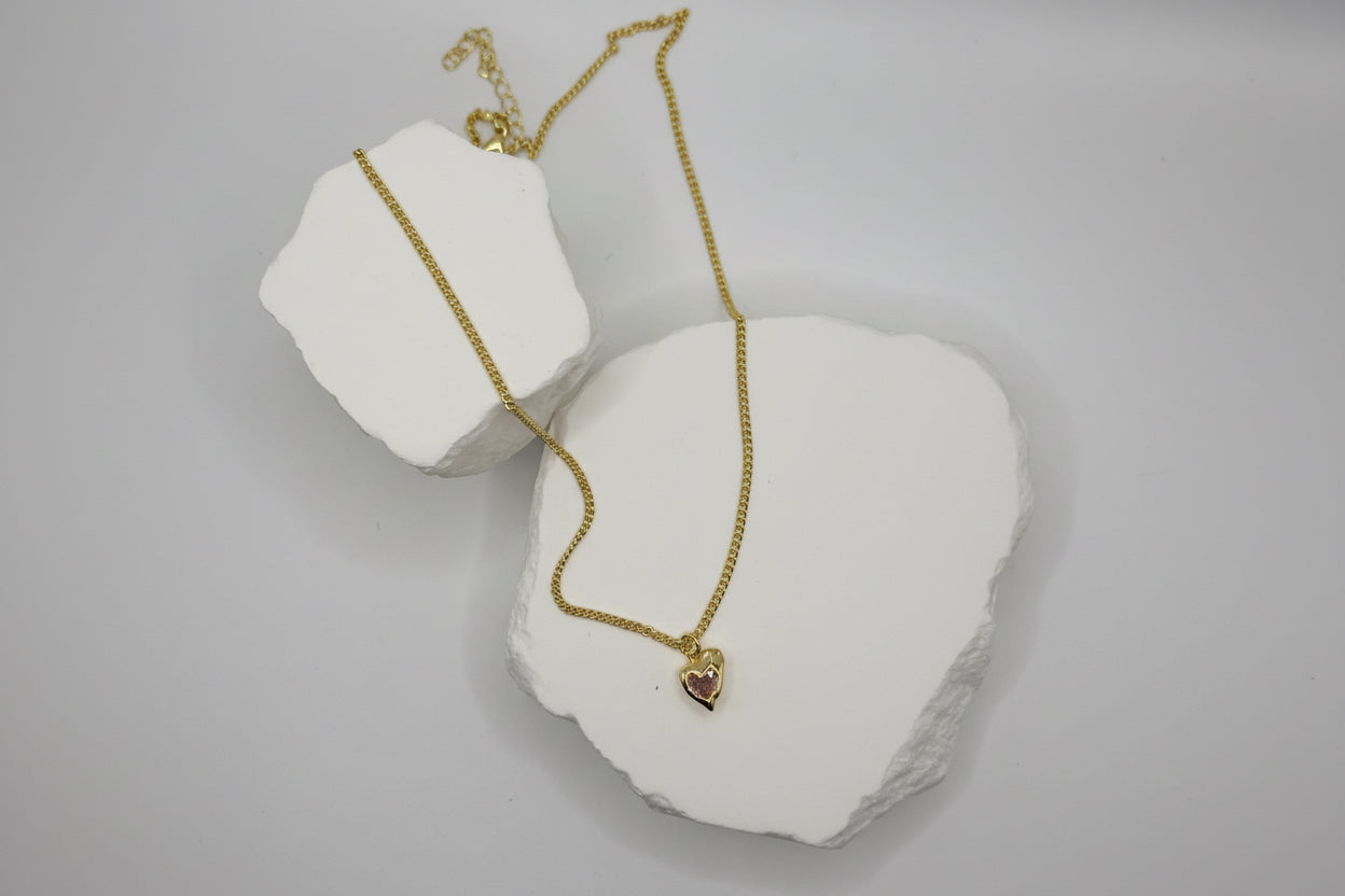 Gold necklace on a white stone surface
