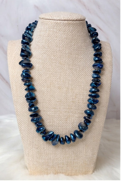Blue beaded quartz necklace on a beige bust against a white background