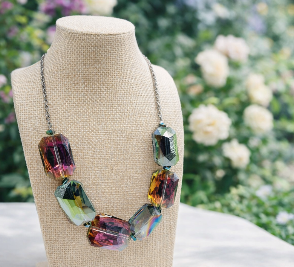 Multicolored crystal necklace on a mannequin bust with a floral background