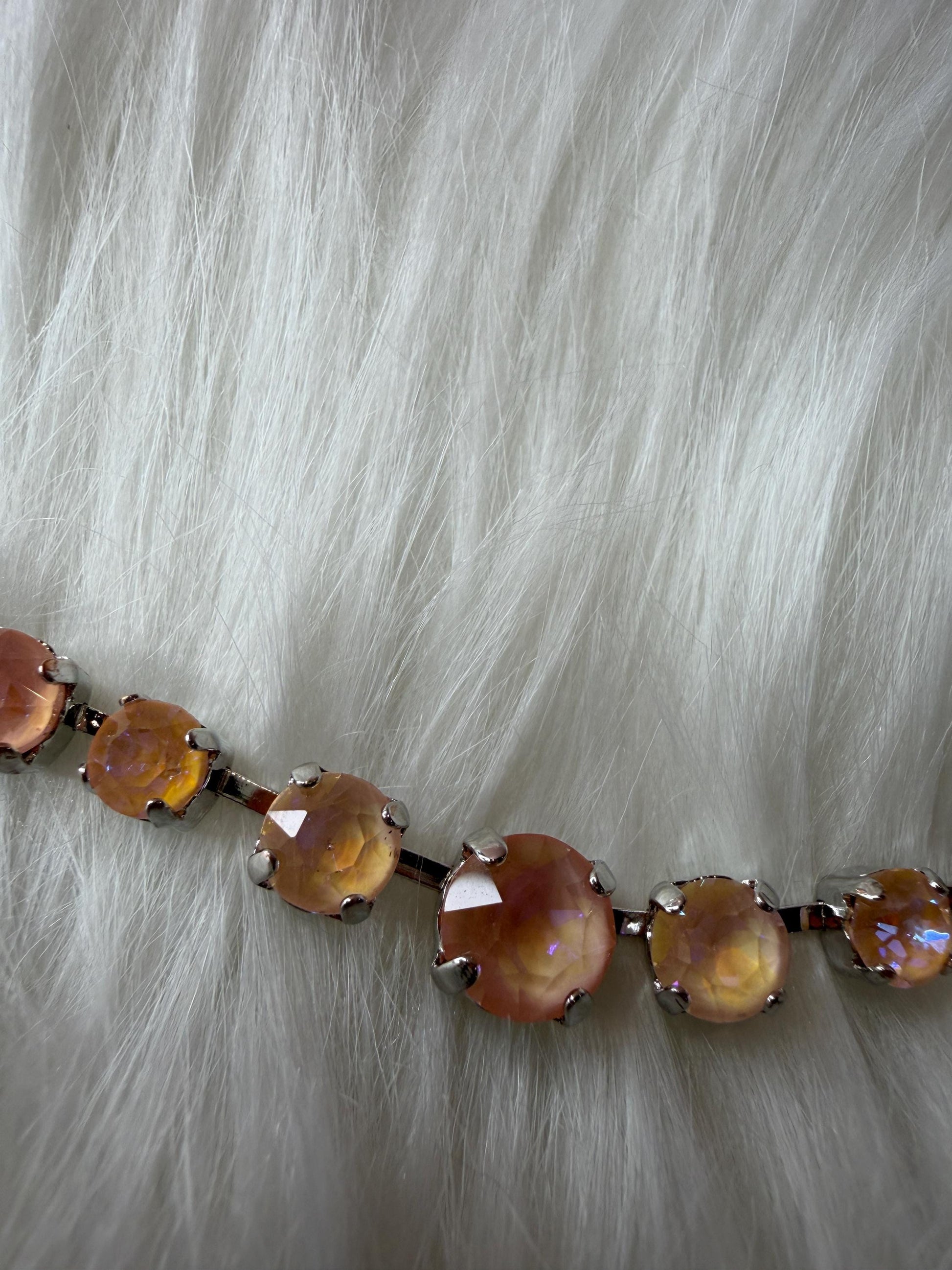 Necklace with peach colored aurora crystals on a fur background