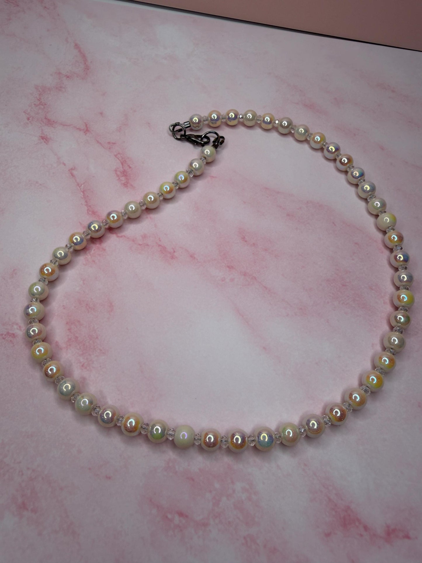 Pearl necklace on a pink marbled surface