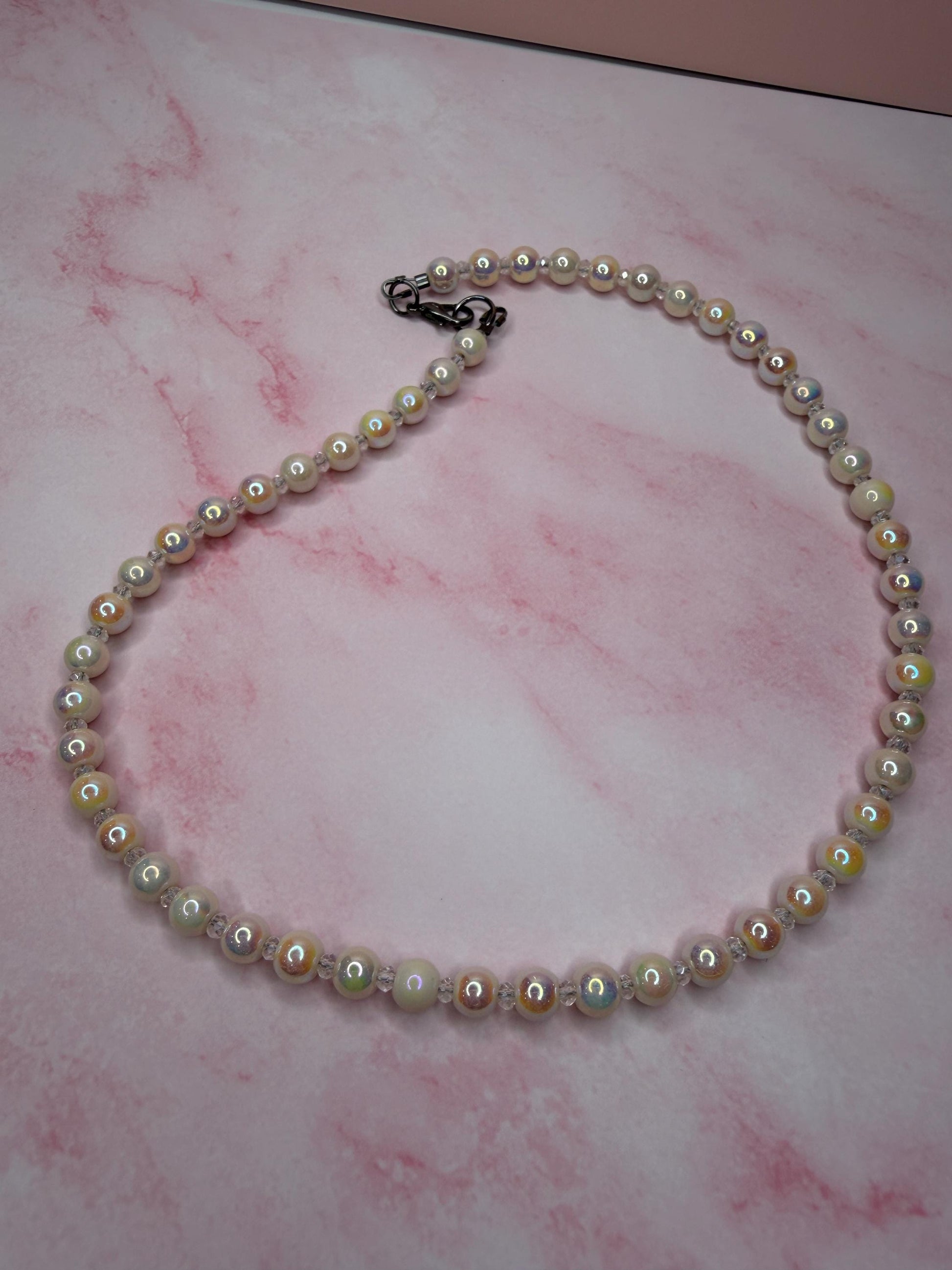 Pearl necklace on a pink marbled surface