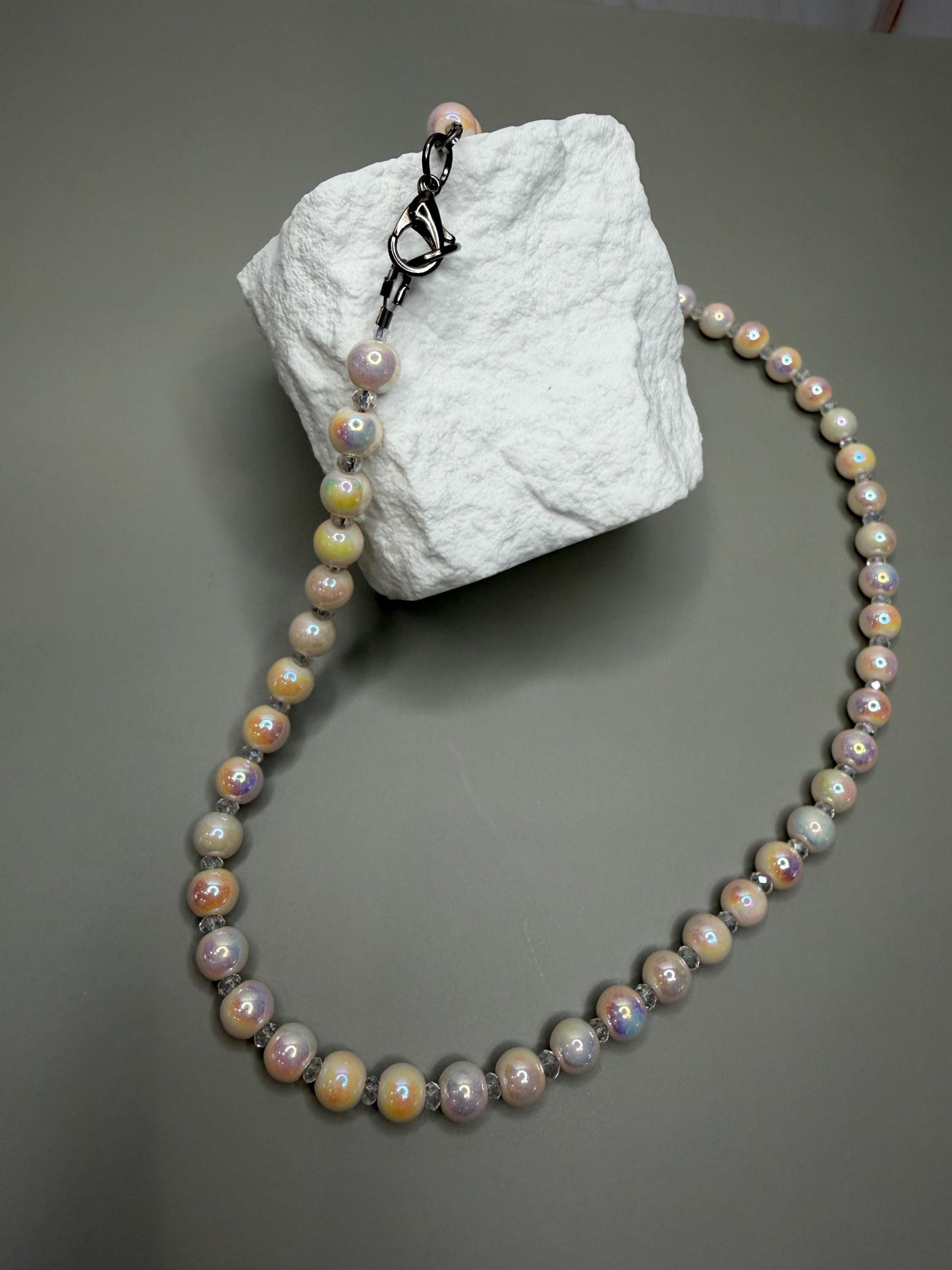 Pearl necklace on a textured white block against a gray background