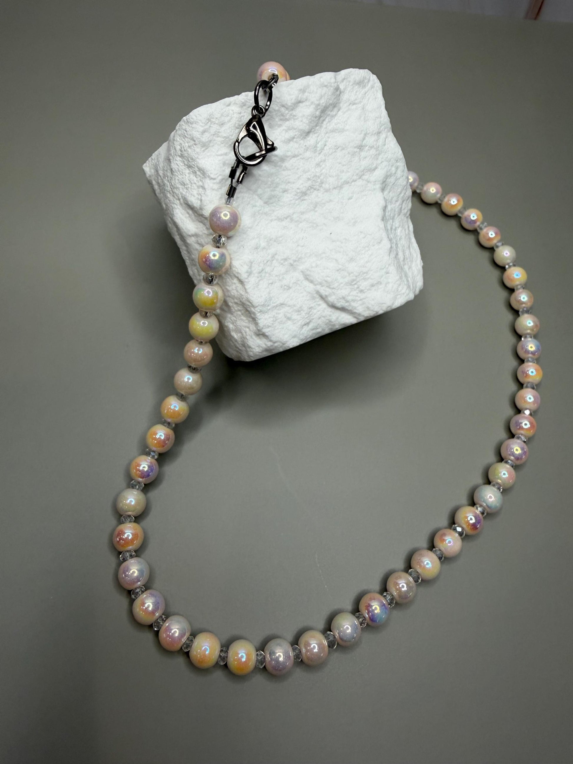 Pearl necklace on a textured white block against a gray background