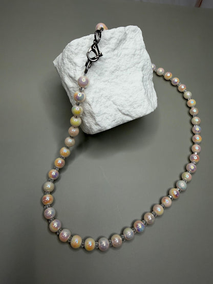 Pearl necklace on a textured white block against a gray background