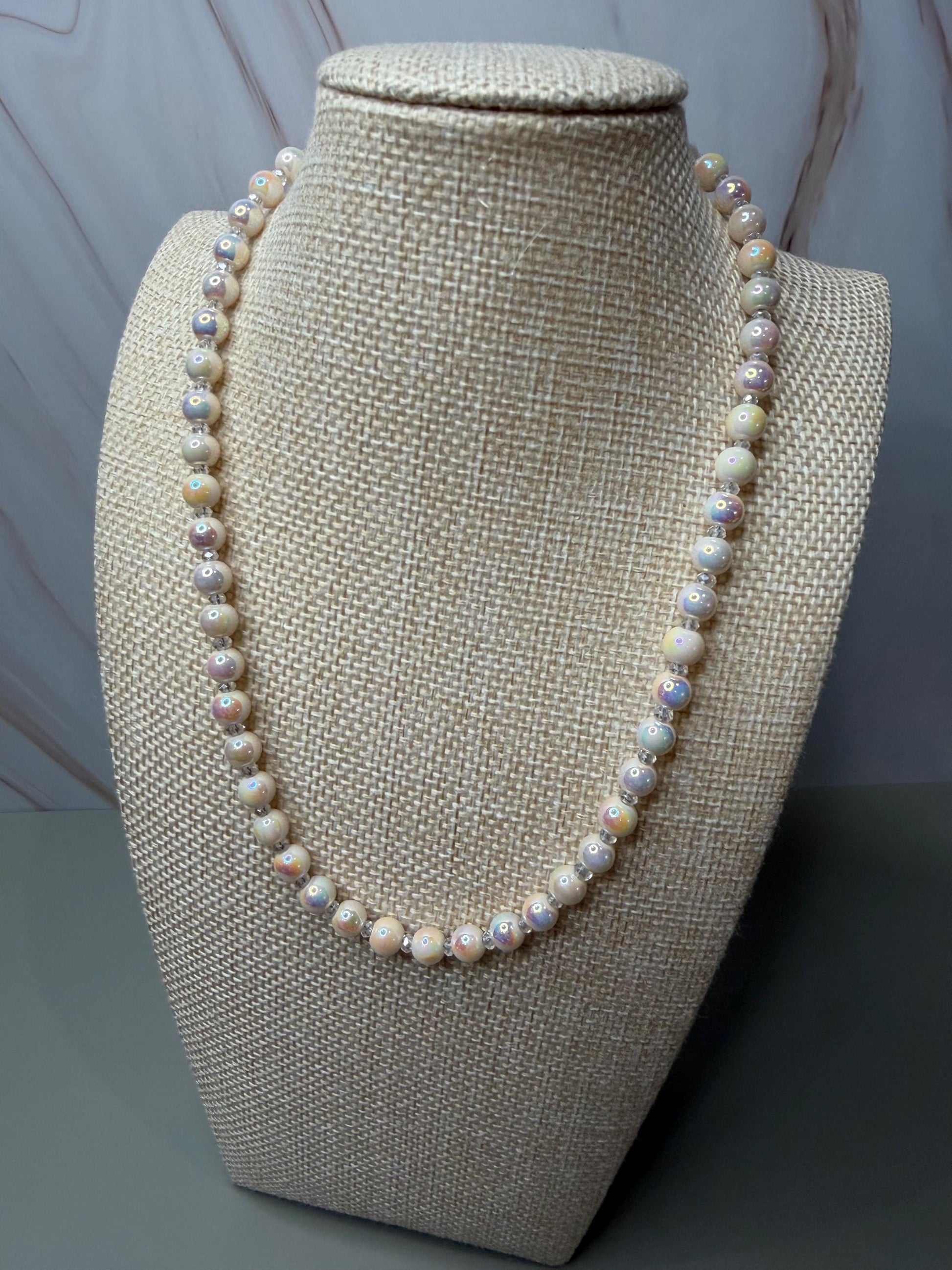Pearl necklace on a beige mannequin bust against a gray background