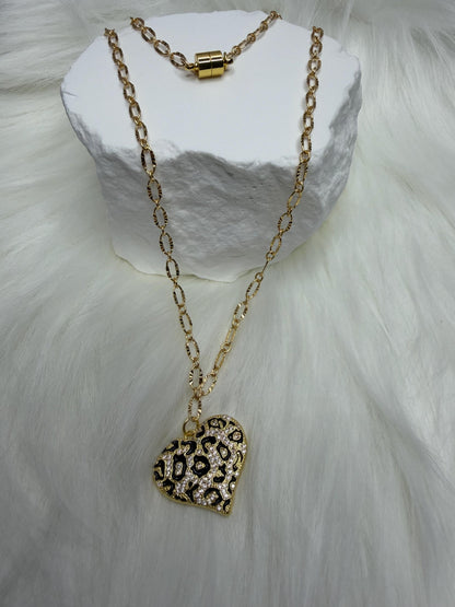 Gold necklace with a heart-shaped leopard print pendant on a white stone surface.