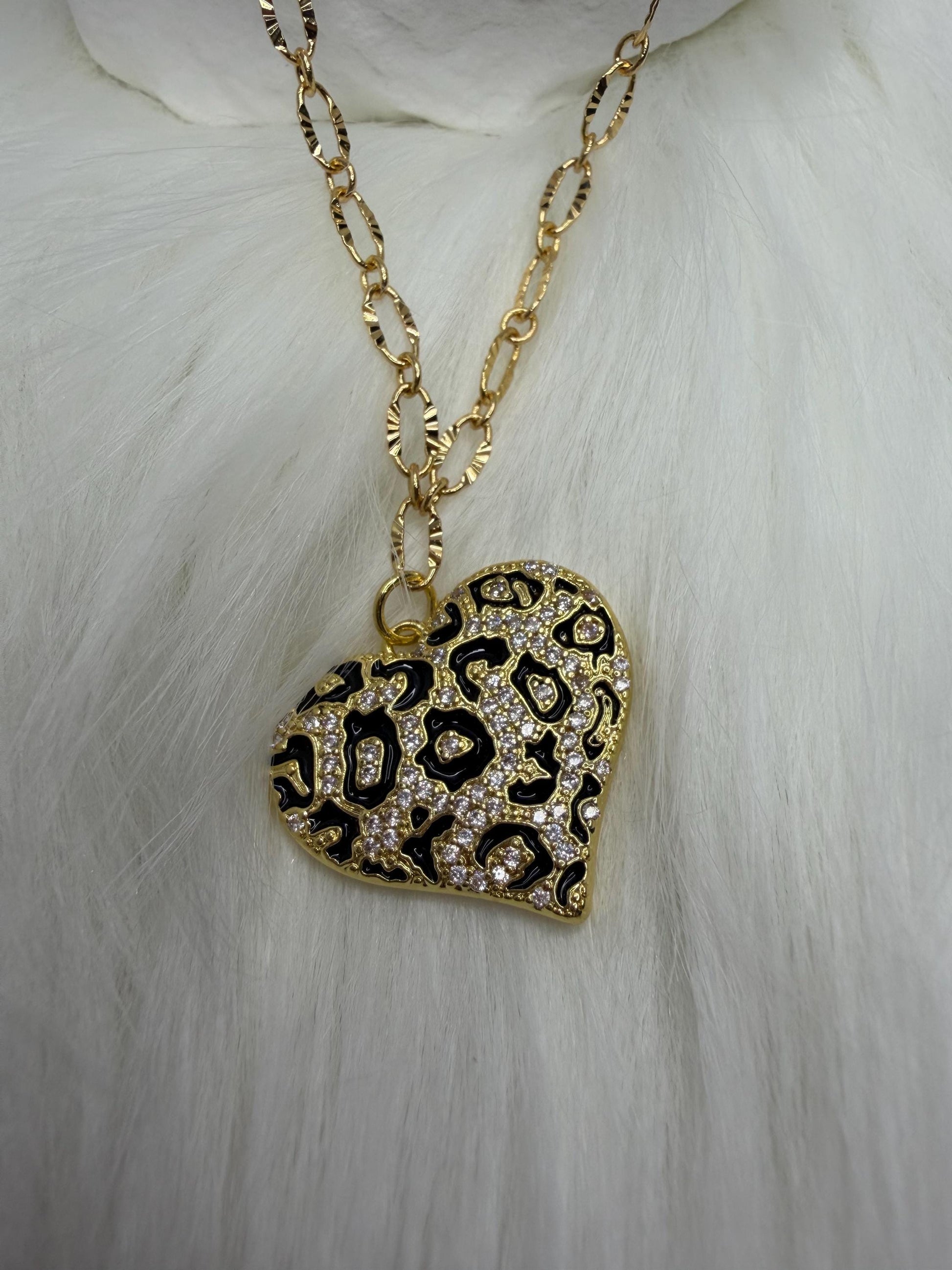 Gold necklace with a leopard print heart pendant on a white fur background