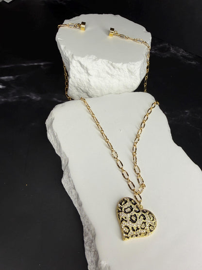 Gold necklace with a heart-shaped pendant on a white stone surface