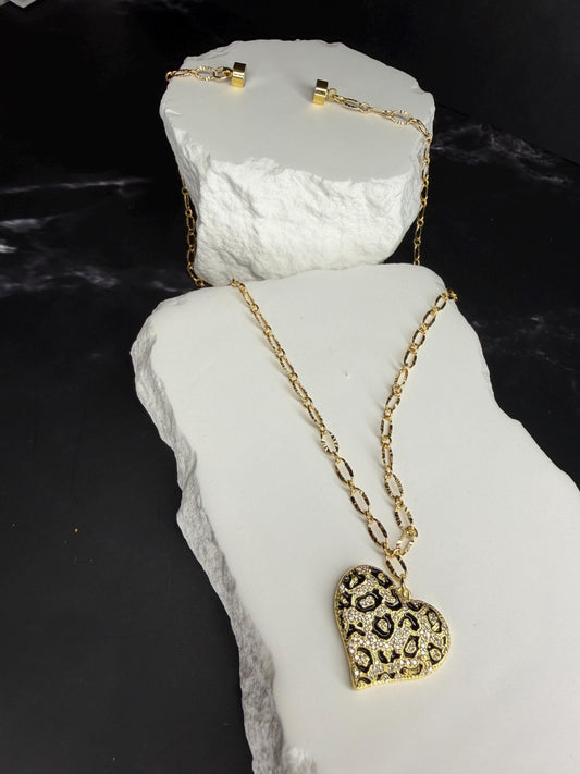 Gold necklace with a heart-shaped pendant on a white stone surface