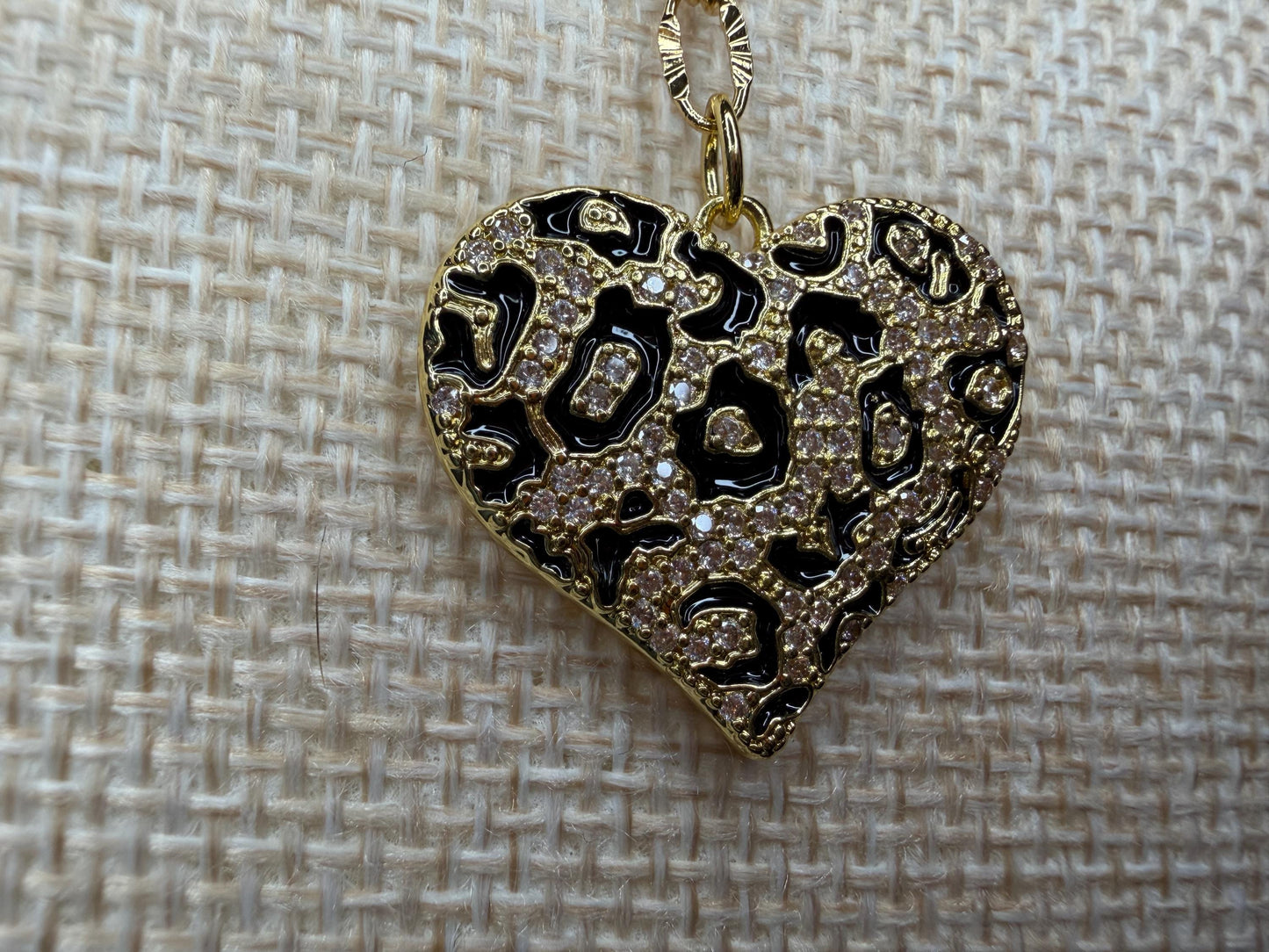 Heart-shaped pendant with intricate designs on a textured beige background