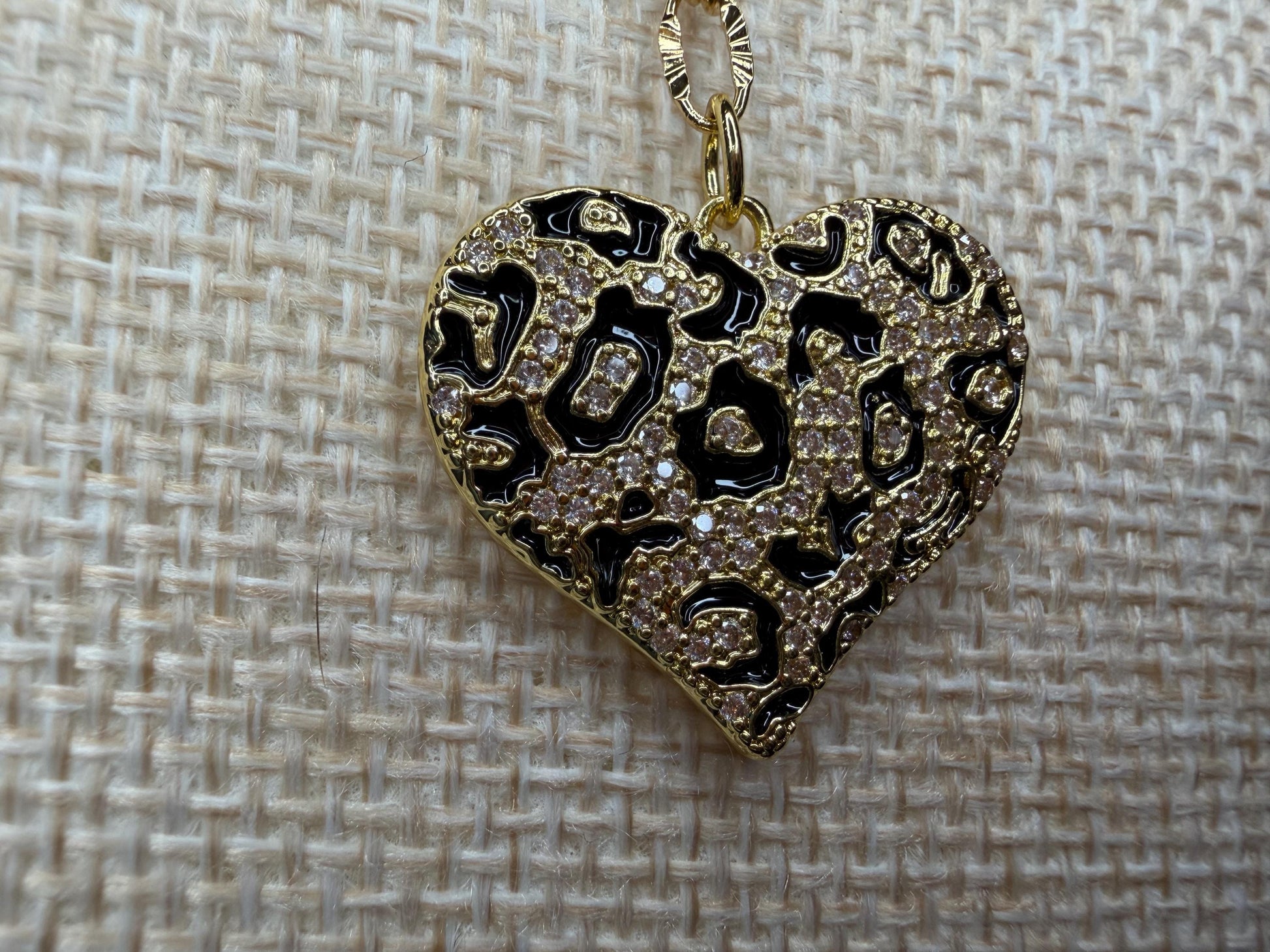 Heart-shaped pendant with intricate designs on a textured beige background