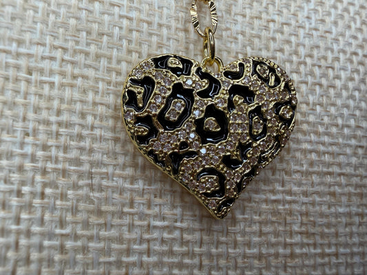 Heart-shaped pendant with intricate designs on a textured beige background