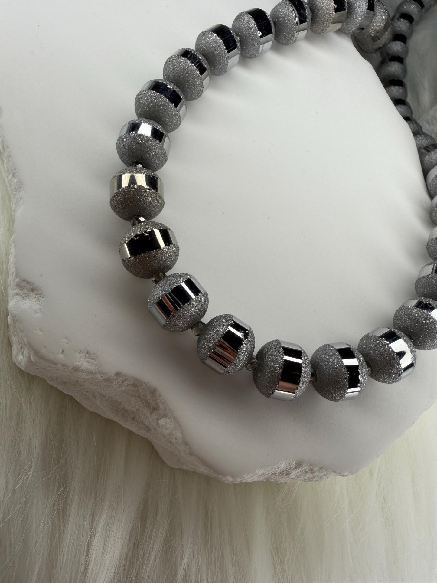 Gray beaded necklace on a white stone surface