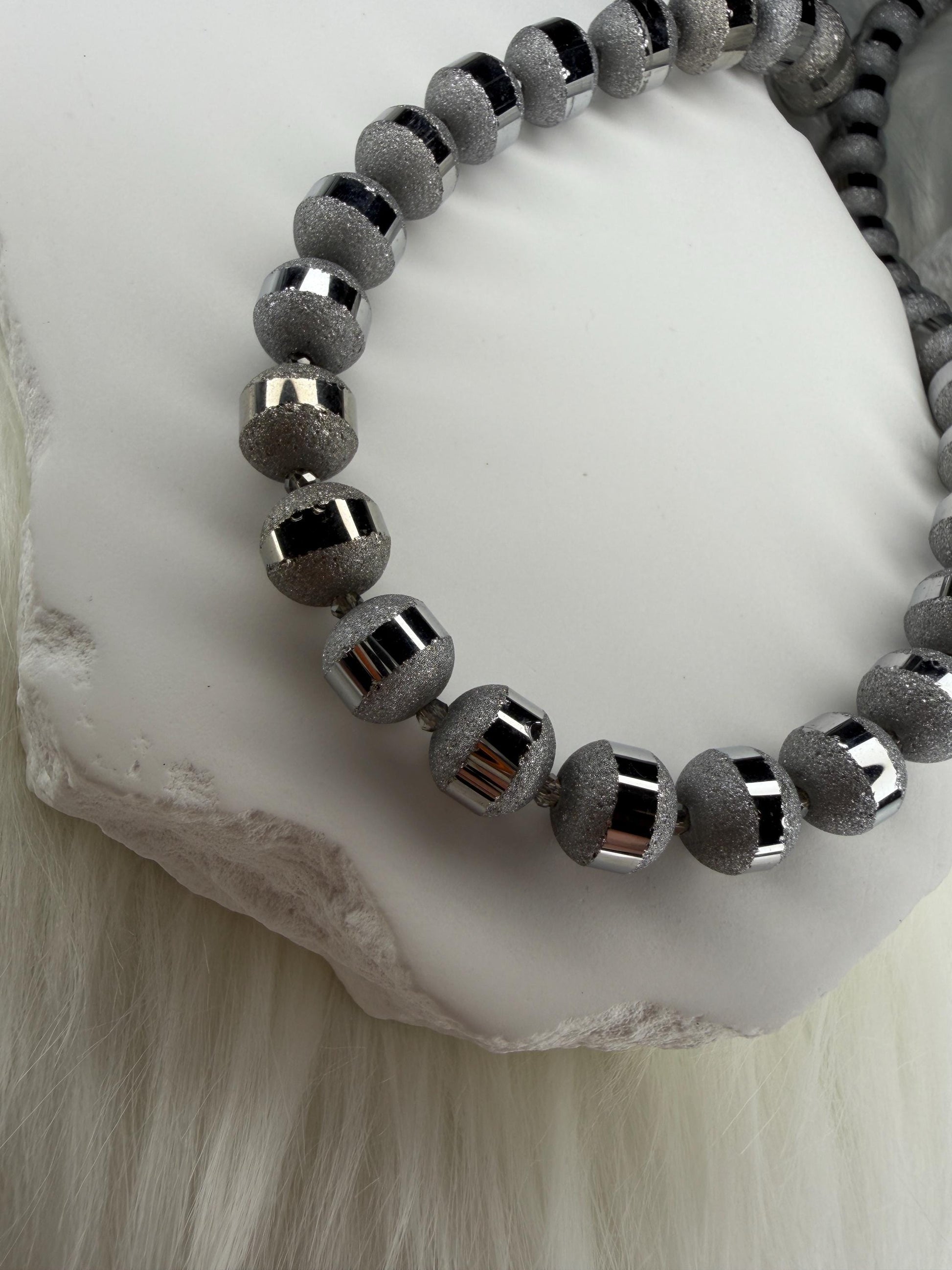 Gray beaded necklace on a white stone surface