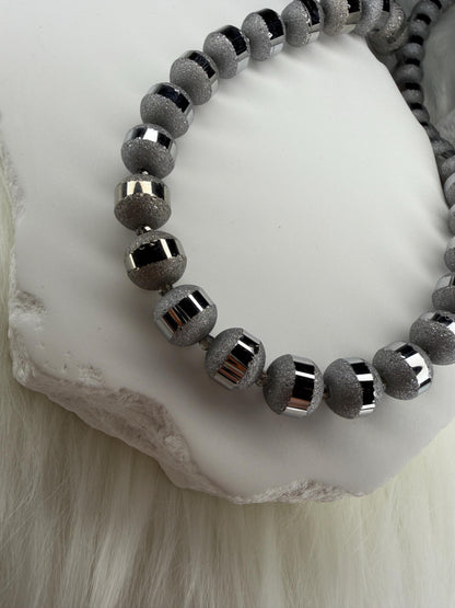 Gray beaded necklace on a white stone surface