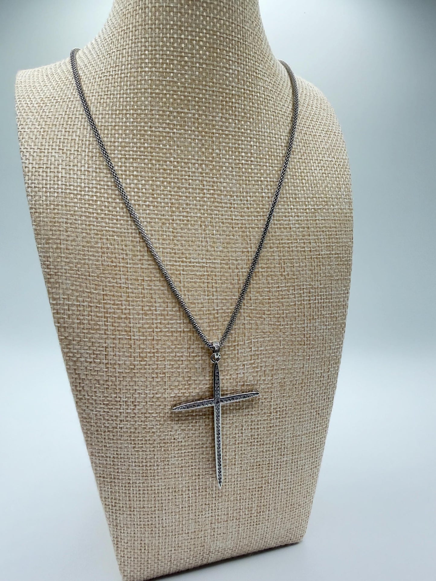 silver Necklace with a silver and cubic zirconia cross pendant on a mannequin bust against a neutral background
