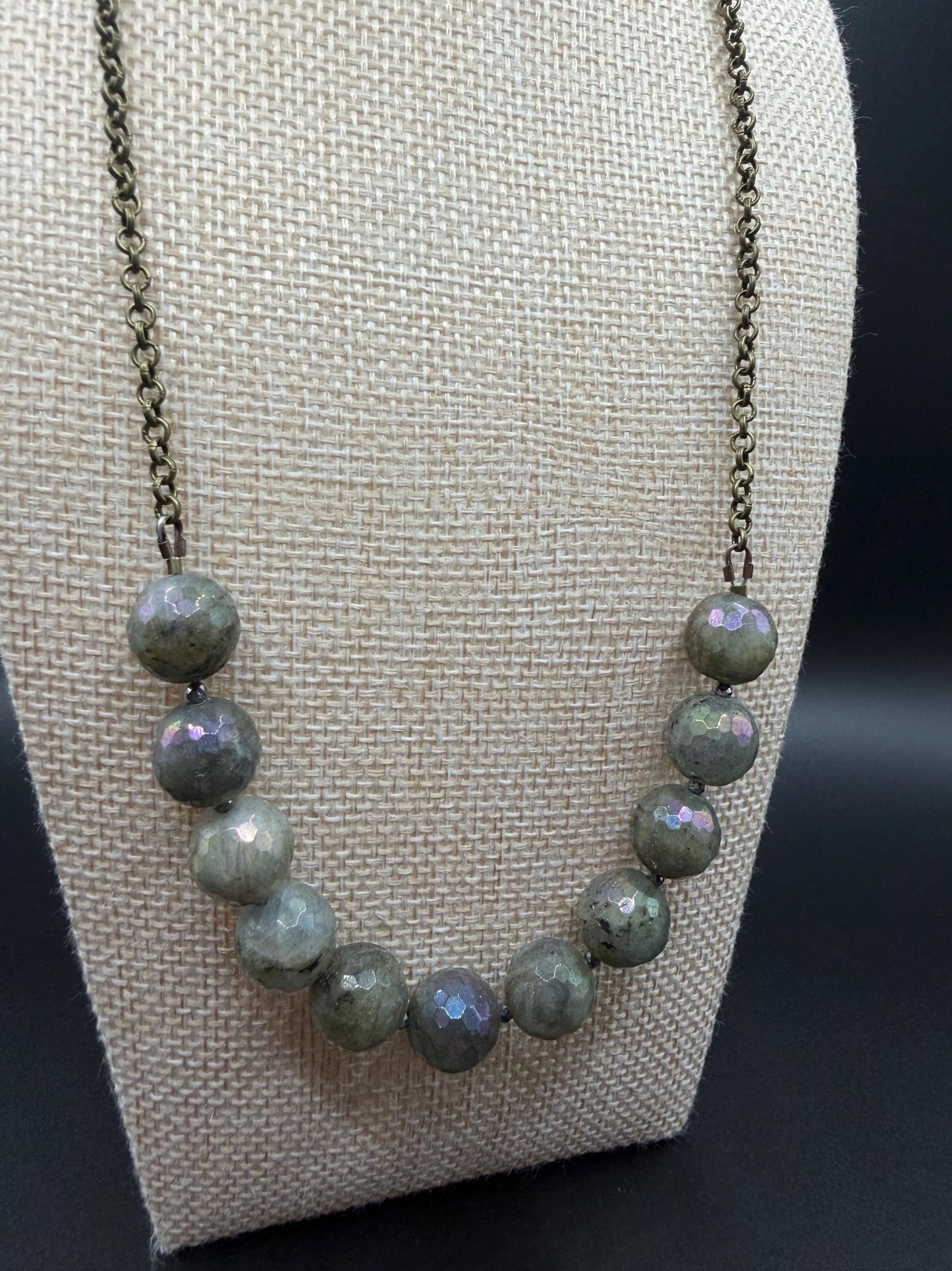 Necklace with green beads on a mannequin bust against a dark background
