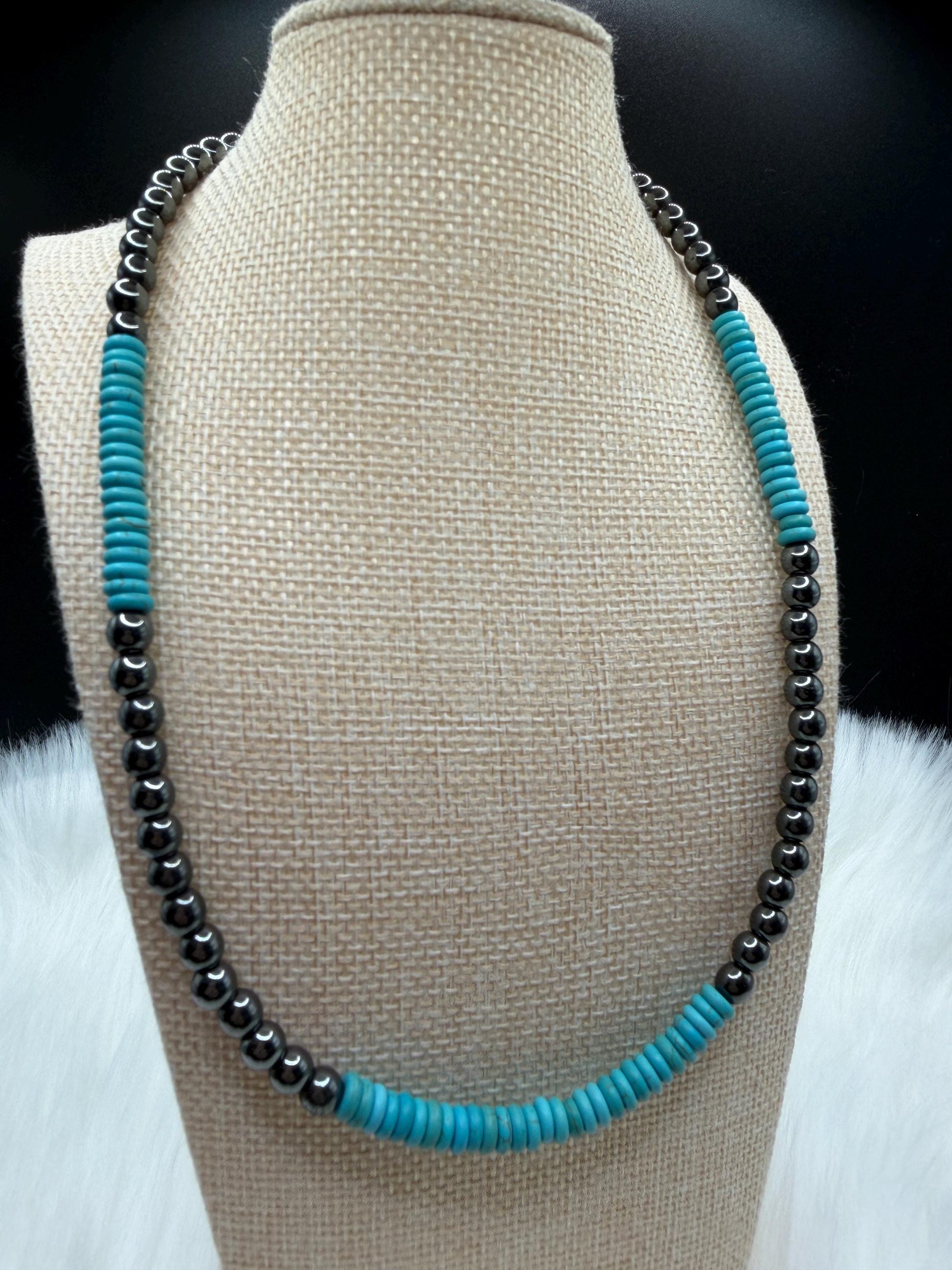 Necklace with turquoise and hematite beads on a beige bust