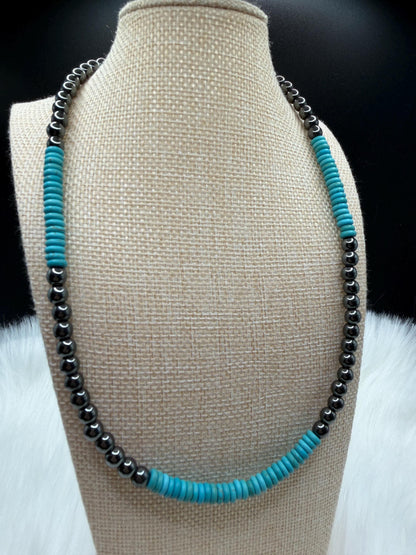 Necklace with turquoise and hematite beads on a beige bust