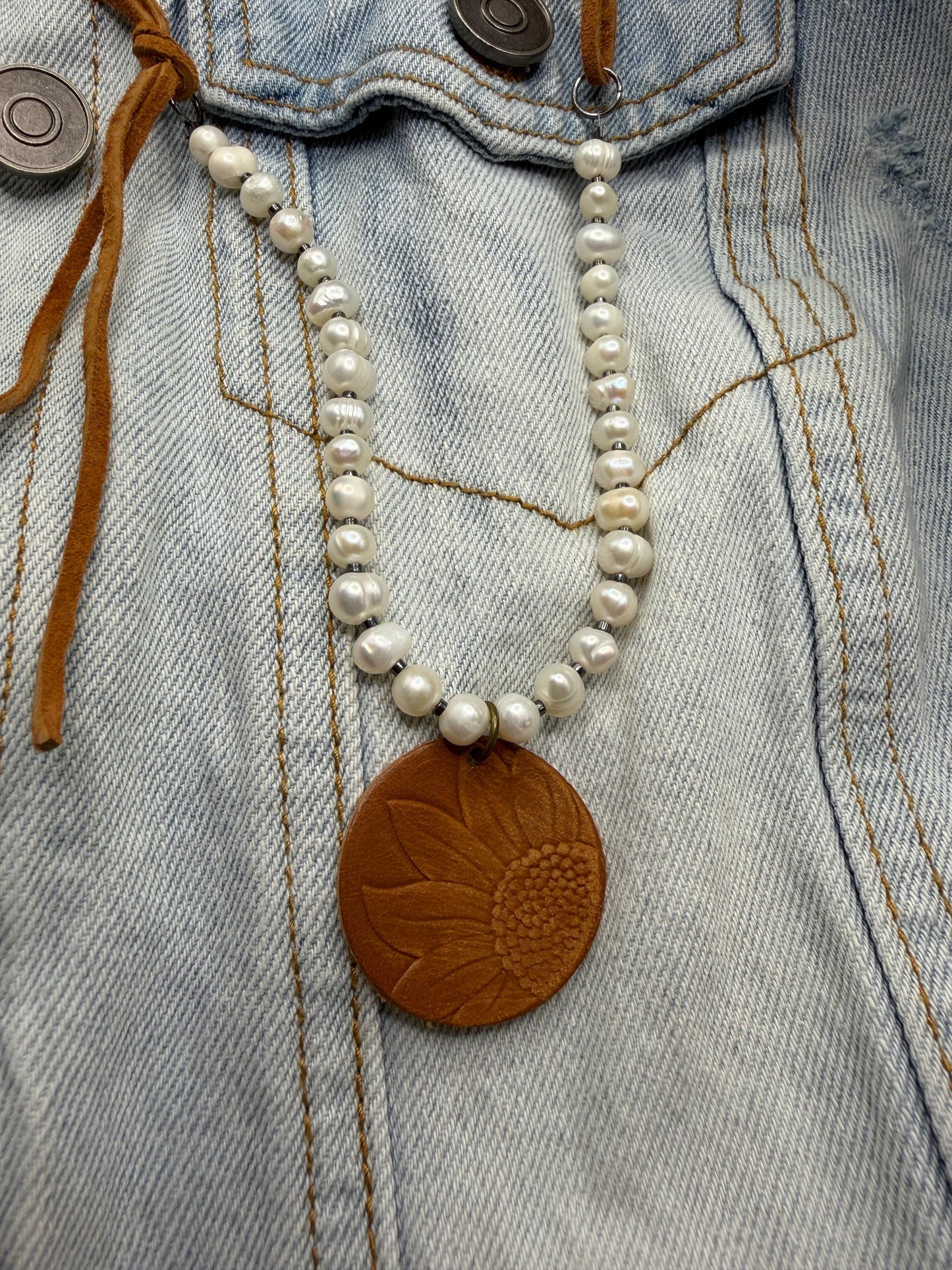 Pearl necklace with a brown leather pendant on denim fabric