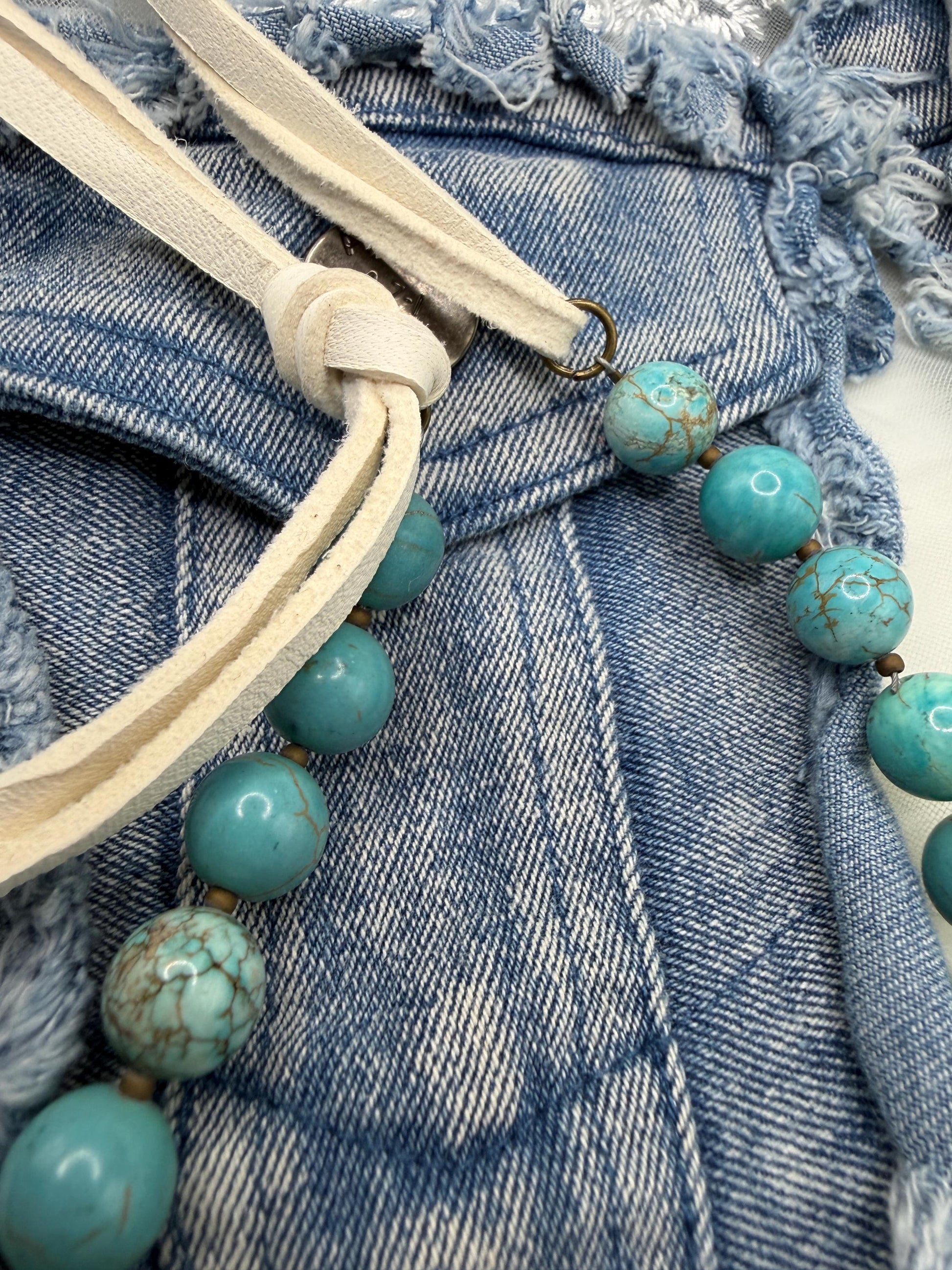 Turquoise beaded strap with leather finish on a denim background