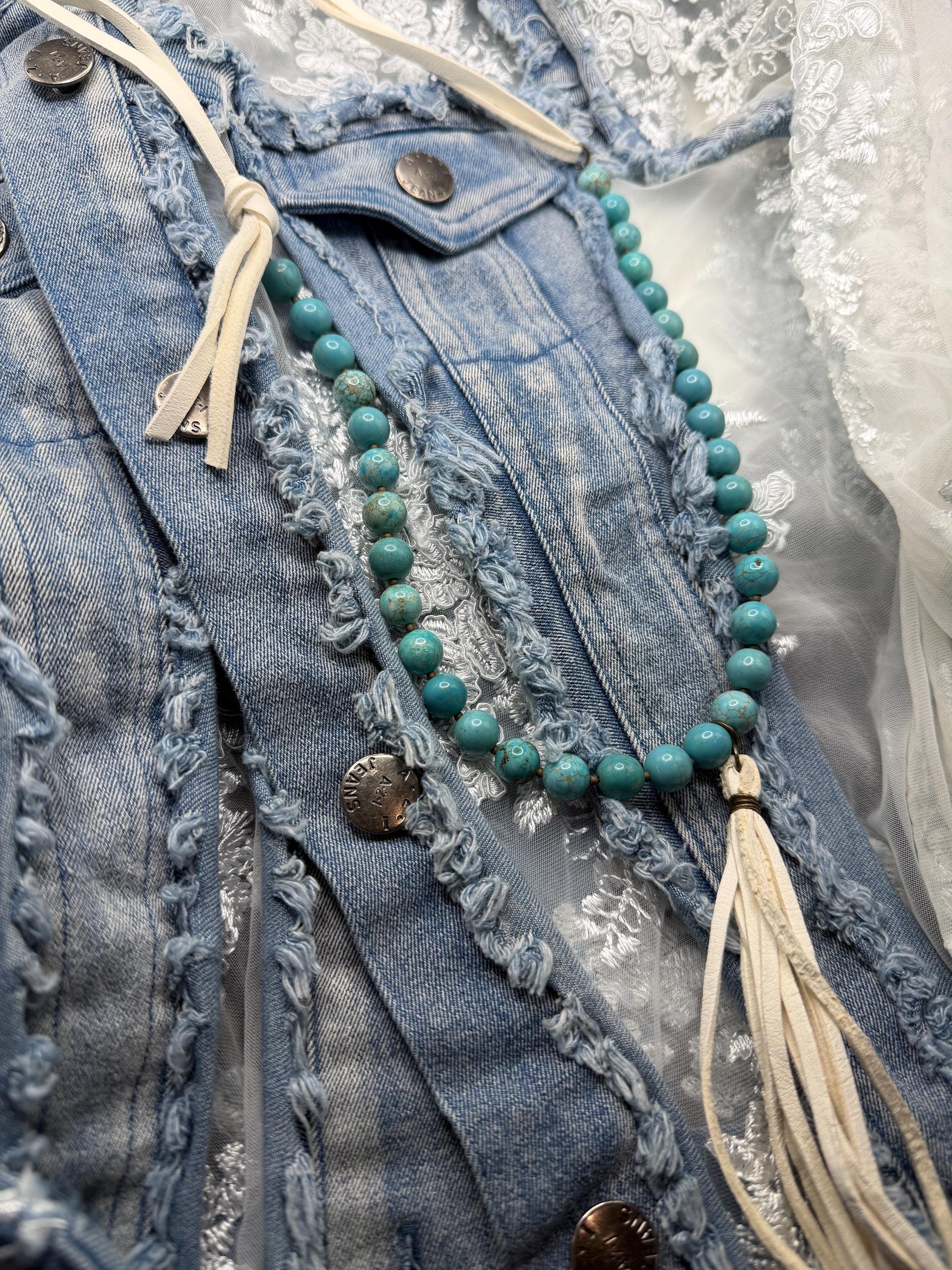 Turquoise beaded necklace with tassel on a denim jacket