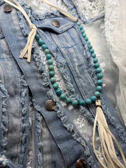 Turquoise beaded necklace with tassel on a denim jacket