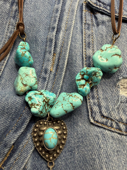 Turquoise stone necklace with a heart-shaped pendant on a denim background