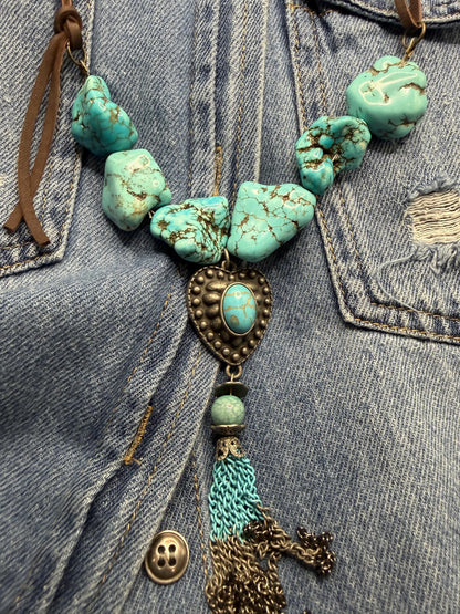 Turquoise beaded necklace with tassel on denim fabric