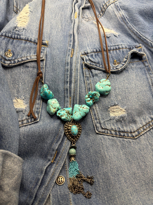 Turquoise beaded necklace with tassel on a denim jacket