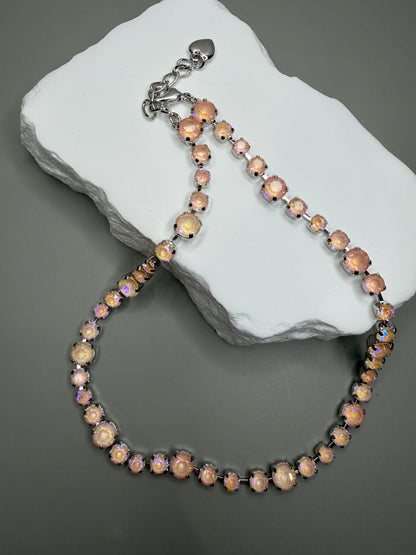 Necklace with pink aurora crystals on a gray stone surface