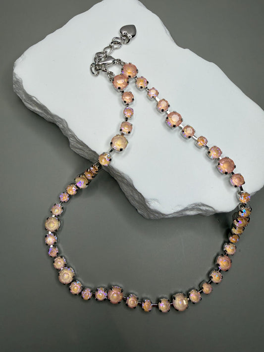 Necklace with pink aurora crystals on a gray stone surface