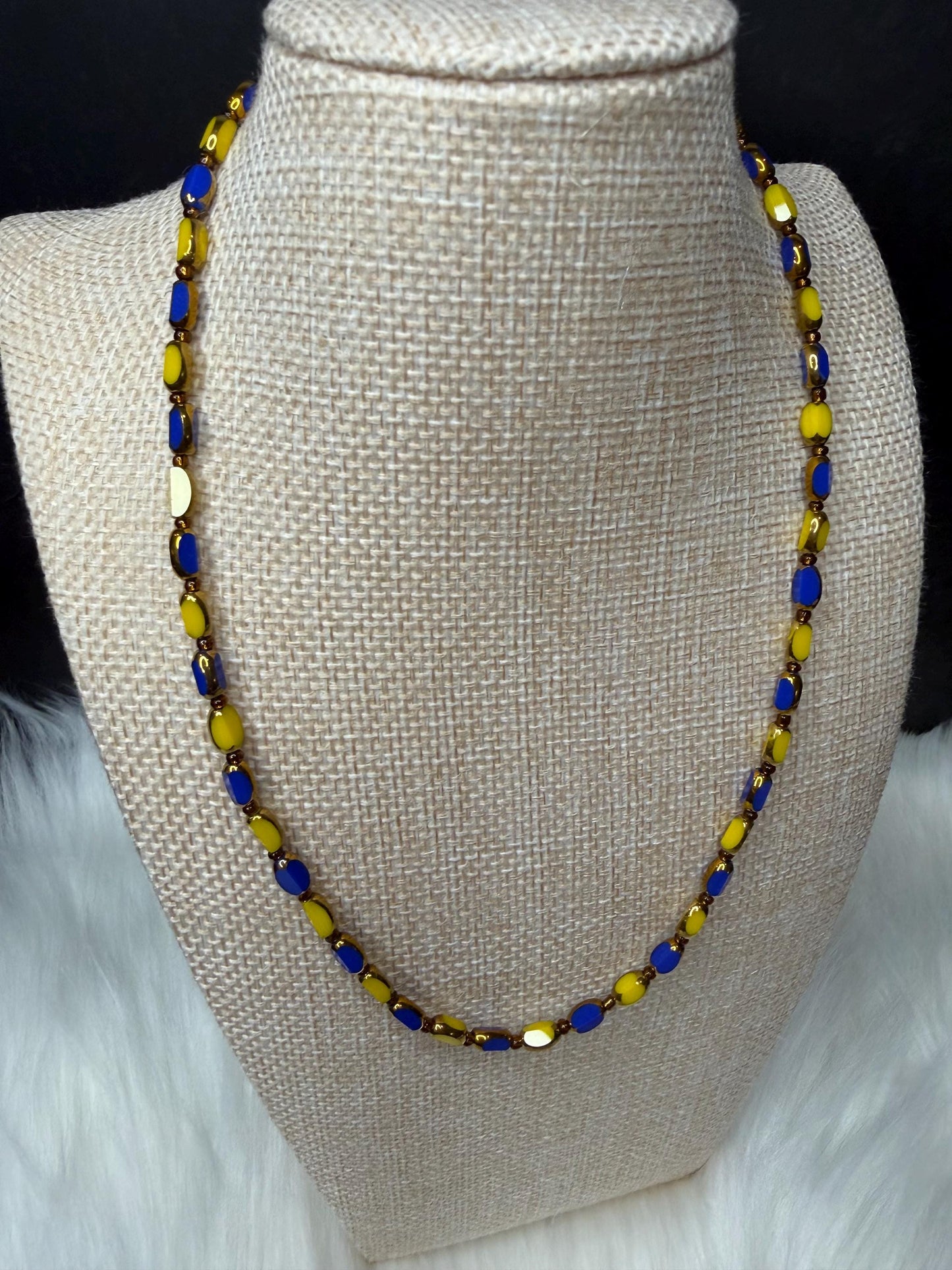 Necklace with blue and yellow beads on a mannequin bust.